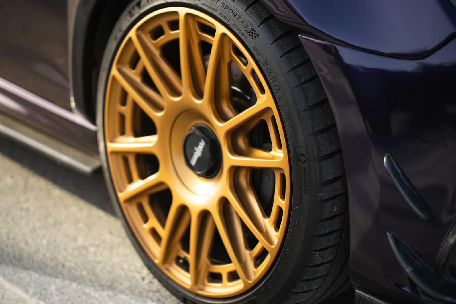 A gold performance wheel on a detailed car