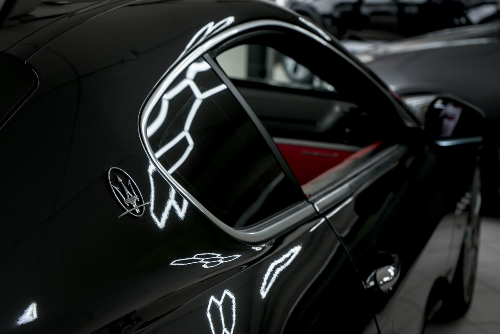 A dark car body panel with mirror-like reflections
